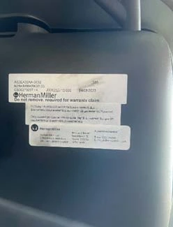 Manufacturing label under the seat of a Herman Miller chair showing the model number, order number and manufacture date