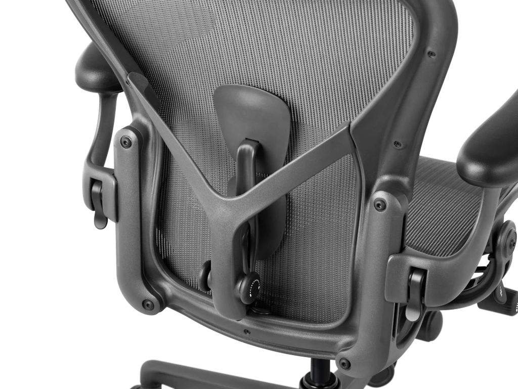 Herman Miller Aeron office chair in graphite at a three-quarter angle from the back, a performance chair covered by the 12-year, 3-shift warranty